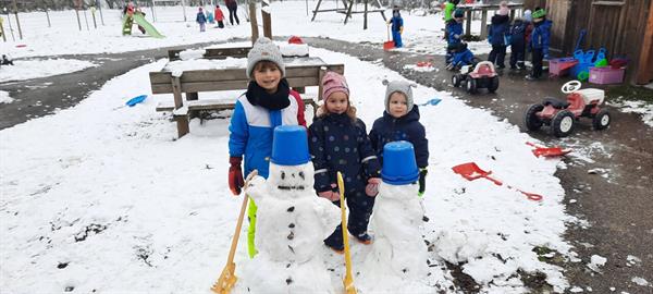 Eine Gruppe von Kindern posiert mit einem Schneemann